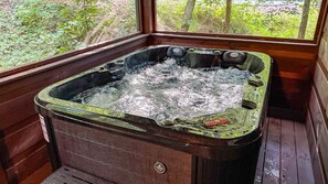 A hot tub with a wooden exterior and a window view of greenery.