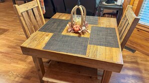 A wooden dining table with a checkered table runner and a decorative centerpiece.