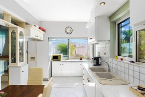 A modern kitchen with white cabinetry, a built-in microwave, and a large window offering a view of the outdoors. - Superior Apartment - Overlooking Chania-with Pool (Chania)