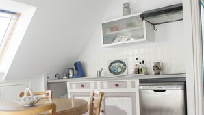 A kitchen with a dining table and chairs, a dishwasher, and a window with a view of the outdoors. - Self-contained apartment in Breton house (Loctudy)