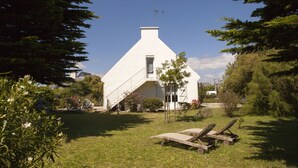 A white building with a triangular roof, a staircase leading to a door, and a small tree in front. - Self-contained apartment in Breton house (Loctudy)