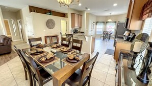 A spacious dining area with a glass table, wooden chairs, and a chandelier. - Palace Retreat - Private Pool/Spa & 24/7 Support (Davenport)