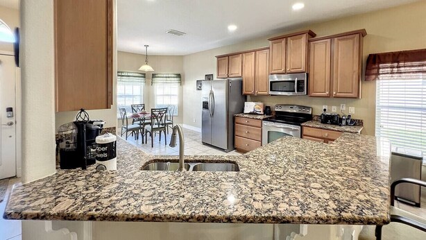A modern kitchen with granite countertops, stainless steel appliances, and wooden cabinets. - Palace Retreat - Private Pool/Spa & 24/7 Support (Davenport)