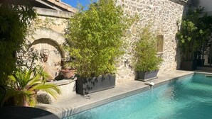 Une piscine avec des murs en pierre et des plantes en pot.