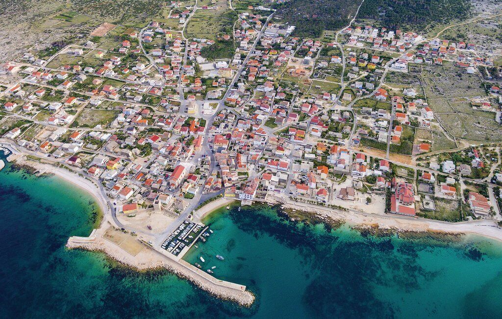 An aerial view of a coastal town with residential buildings, a marina, and a beach.