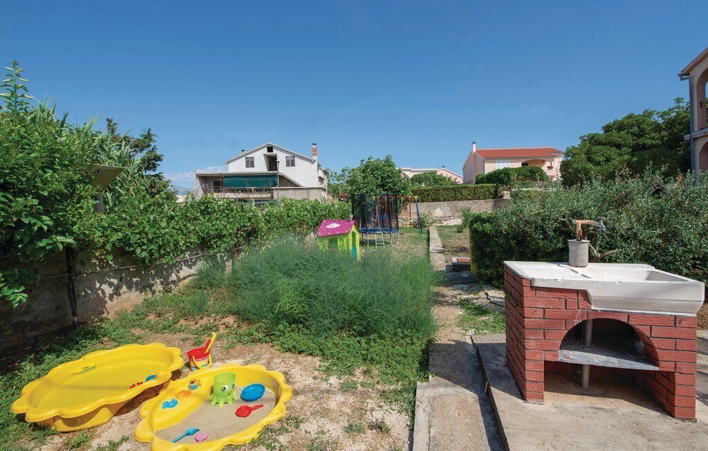 Ein Garten mit Lehmofen, Spielgeräten und einem kleinen Pool.