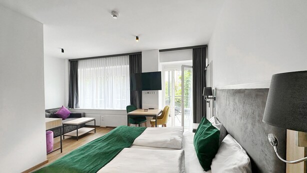 A hotel room with two beds, a desk, a chair, a TV, and a balcony with a view. - DORMERO Hotel Rüsselsheim (Ruesselsheim)