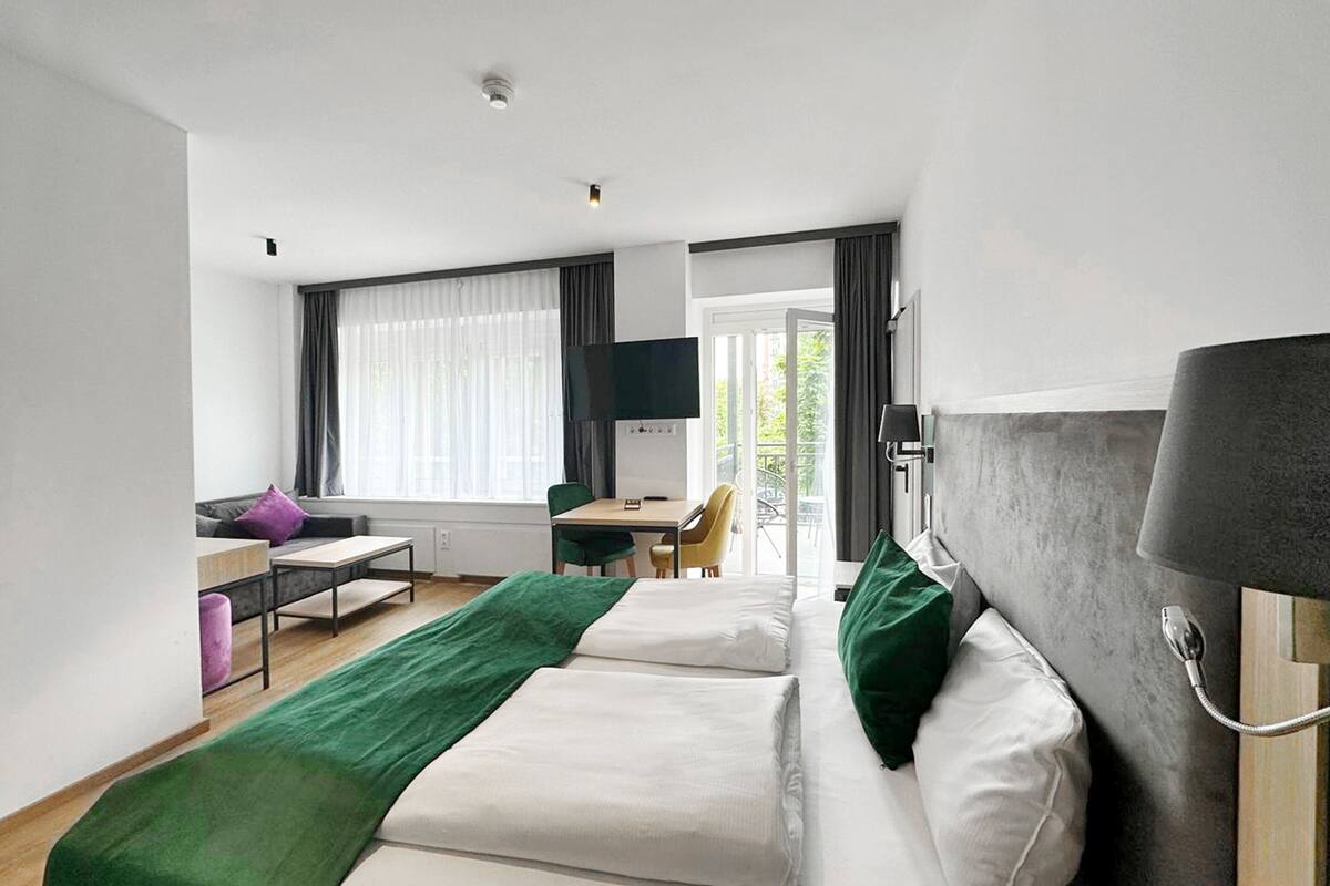 Une chambre d’hôtel avec deux lits, un bureau, une chaise, une télévision et un balcon avec vue.