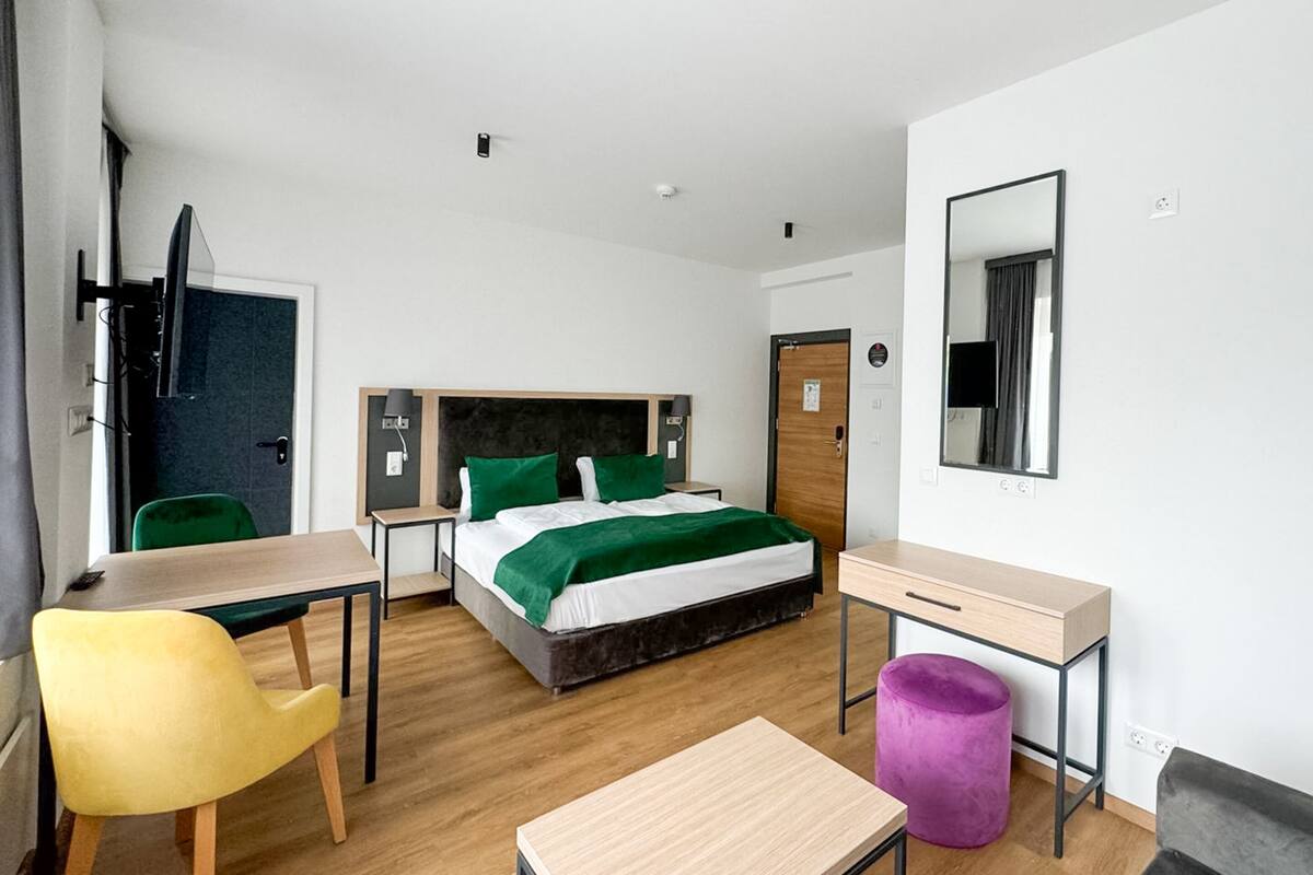 Une chambre d’hôtel moderne équipée d’un lit, d’un bureau, d’une chaise et d’une petite table.
