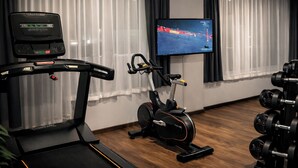 A home gym with a treadmill, stationary bike, and weight bench. - DORMERO Hotel Rüsselsheim (Ruesselsheim)