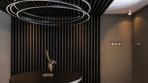A modern interior with a circular table, vertical wooden slats, and a ceiling light fixture. - Hotel mischun (Brigels)