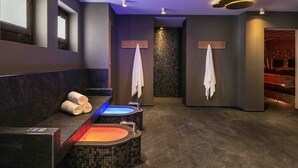 A modern bathroom with two hot tubs, a large mirror, and a tiled wall. - Hotel mischun (Brigels)