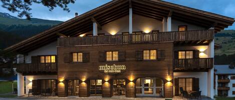 A two-story building with a wooden facade and balconies, named "Mischum."