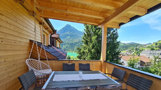 Eine Holzterrasse mit Tisch und Stühlen, mit Blick auf eine Berglandschaft.