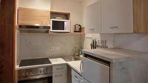 Eine kompakte Küche mit integriertem Mikrowellenherd, Herd, Backofen und Kühlschrank.