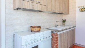 A kitchen with wooden cabinets, a white stove, a sink, and a decorative basket on the counter.