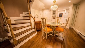 A staircase with wooden steps and a chandelier above a dining table with chairs. - One Such Boston Gem w Pvt Garden (Boston)