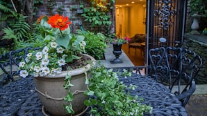 A potted plant with flowers and a metal table in a garden area. - One Such Boston Gem w Pvt Garden (Boston)