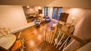 A spacious living area with a wooden floor, a staircase, and a view through large windows. - One Such Boston Gem w Pvt Garden (Boston)