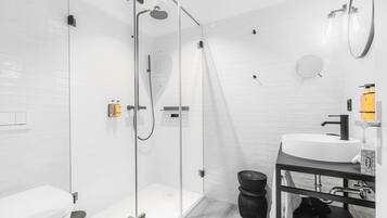 A modern bathroom with a glass-enclosed shower, a white sink, and a toilet.