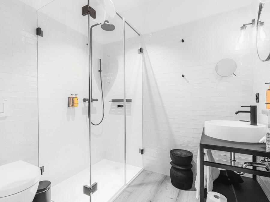 A modern bathroom with a glass-enclosed shower, a white sink, and a toilet.