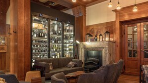 A cozy lounge area with a fireplace, leather seating, and a wine cooler. - ALPINE INN Davos (Davos)