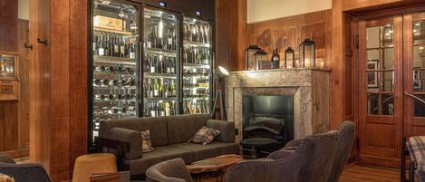 A cozy lounge area with a fireplace, leather seating, and a wine cooler.