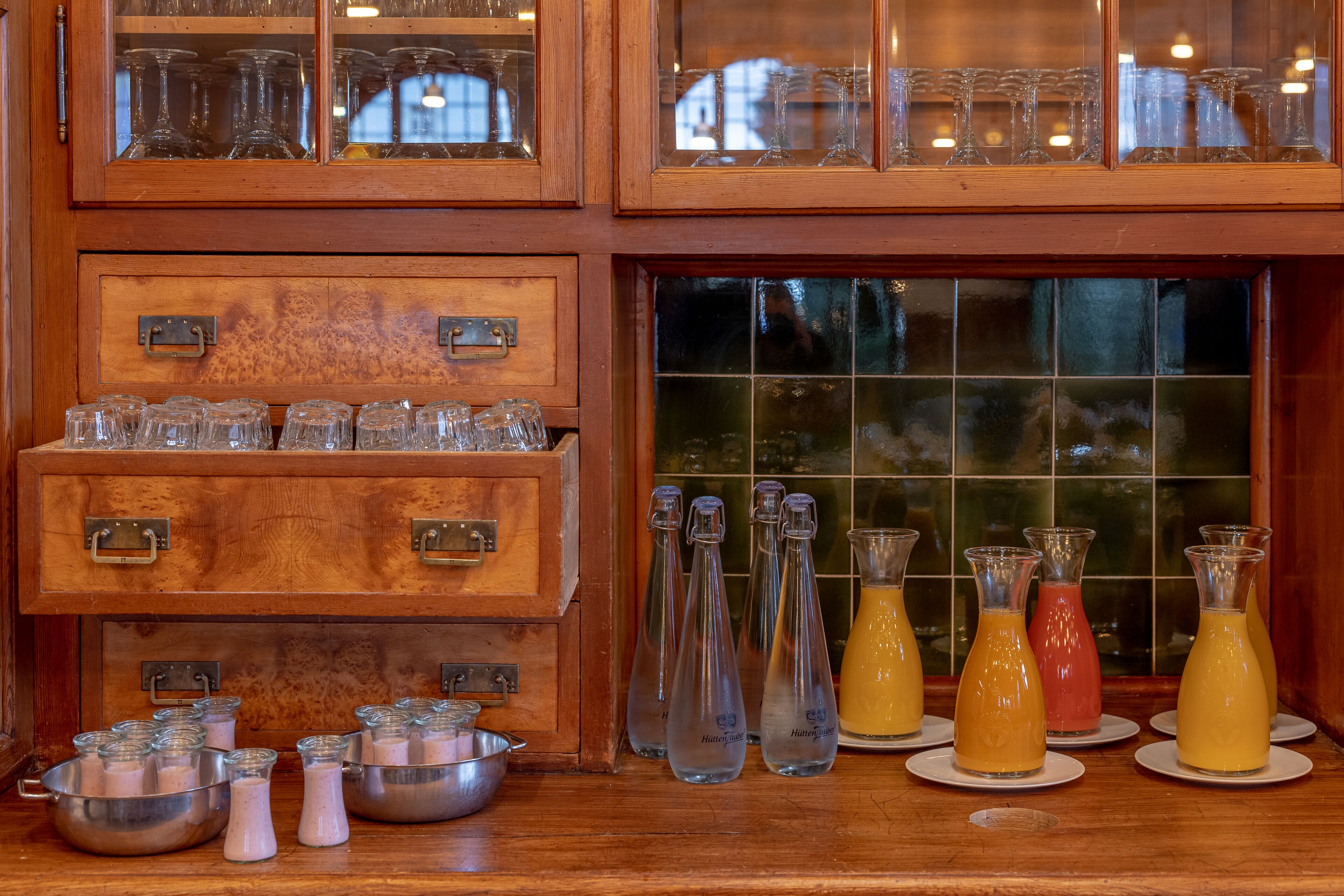 Un espace bar avec des meubles en bois, de la verrerie et diverses bouteilles de boissons.