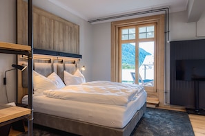 A bedroom with a bed, wooden headboard, a desk, and a TV.