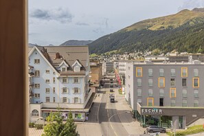 A street view with buildings, a road, and a mountain in the background. - ALPINE INN Davos (Davos)