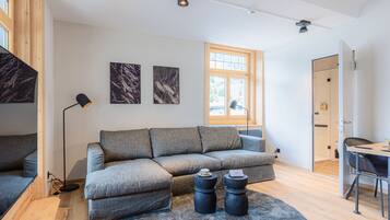 A modern living room with a sectional sofa, a coffee table, and a dining area with a table and chairs.