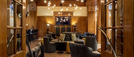 A cozy, wood-paneled room with a sofa, chairs, and a television.
