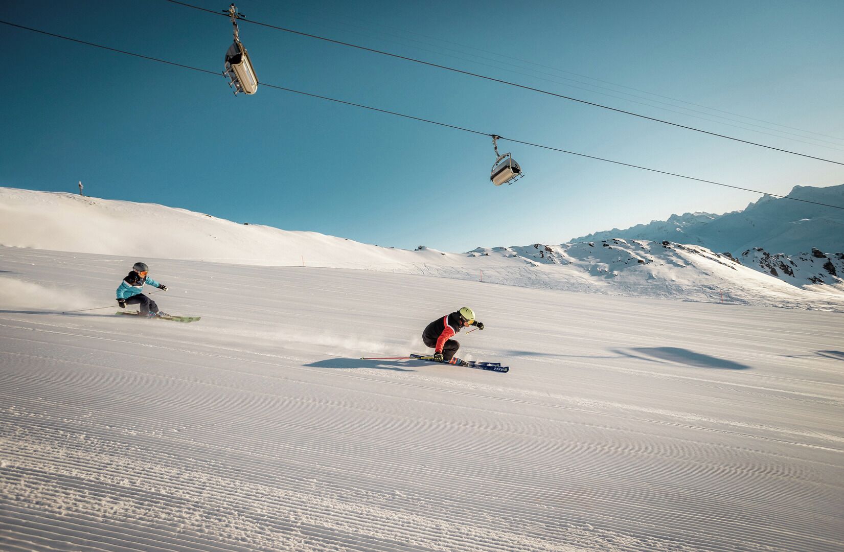 Una pista de esquí con esquiadores y un teleférico al fondo.