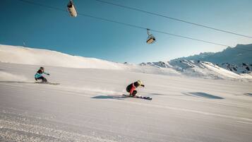 Eine Skipiste mit Skifahrern und einer Seilbahn im Hintergrund.