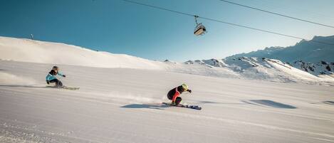 A ski slope with skiers and a cable car in the background.