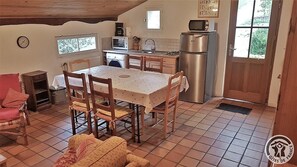 A cozy kitchen with a dining table, chairs, a microwave, a refrigerator, and a washing machine. - Domaine Albert - POMMIERS (POMMIERS)