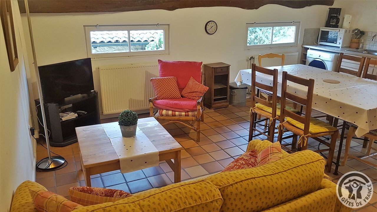 A cozy living room with a sofa, a dining table, a red armchair, and a television.