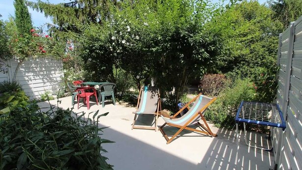 Un jardin avec deux chaises longues, une petite table et une chaise en métal bleue.