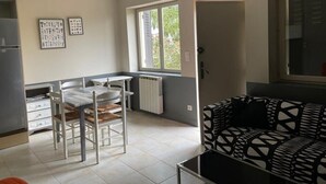 Un espace de vie compact comprenant un coin cuisine, un coin repas et un canapé à motifs.