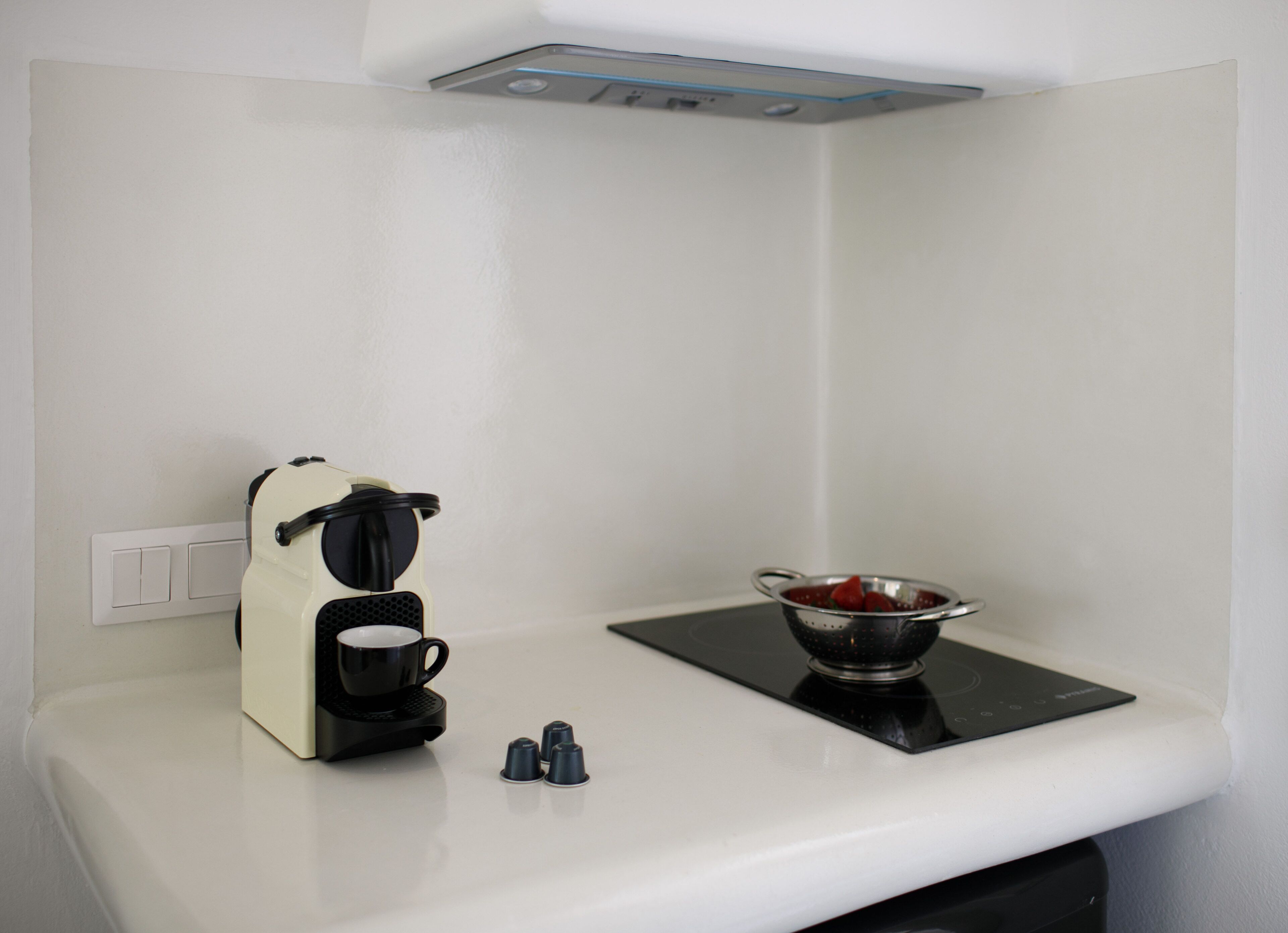 A kitchenette with a coffee maker, a colander, and a small sink.