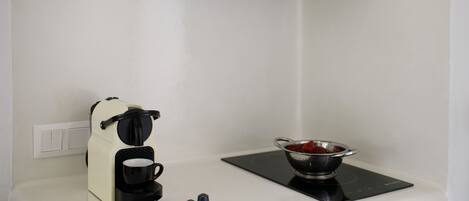 A kitchenette with a coffee maker, a colander, and a small sink.