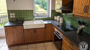 Eine Küche mit Holzschränken, einer Spüle, einem Fenster mit Blick und einer gefliesten Spritzwand.