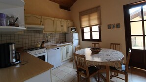 A kitchen with white cabinets, a stove, a microwave, and a dining table with chairs.