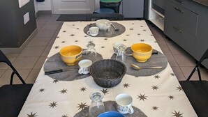 A compact kitchen with a dining area set for four. - Le gîte des Toussillards (TOUSSIEU)