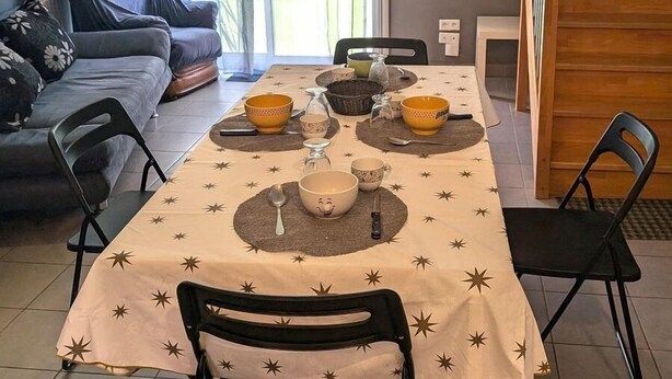 A dining area with a table set for four, featuring star-patterned tablecloths and various bowls and utensils. - Le gîte des Toussillards (TOUSSIEU)