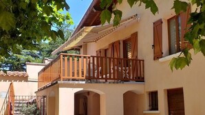 Ein zweistöckiges Gebäude mit einem Balkon, Rundbogenfenstern und einem Ziegeldach.