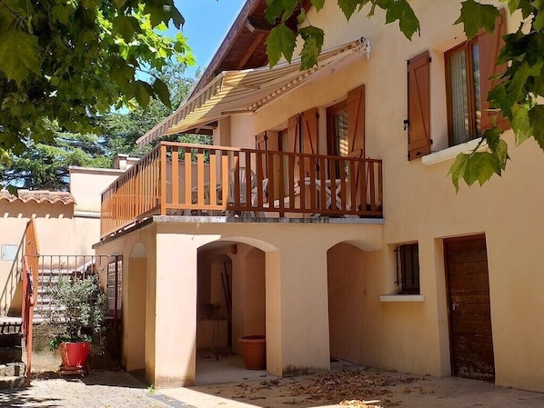 A two-story building with a balcony, arched doorways, and a tiled roof.