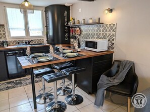 Eine moderne Küche mit Essbereich, inklusive Barhocker, Mikrowelle und einem schwarzen Schrank.