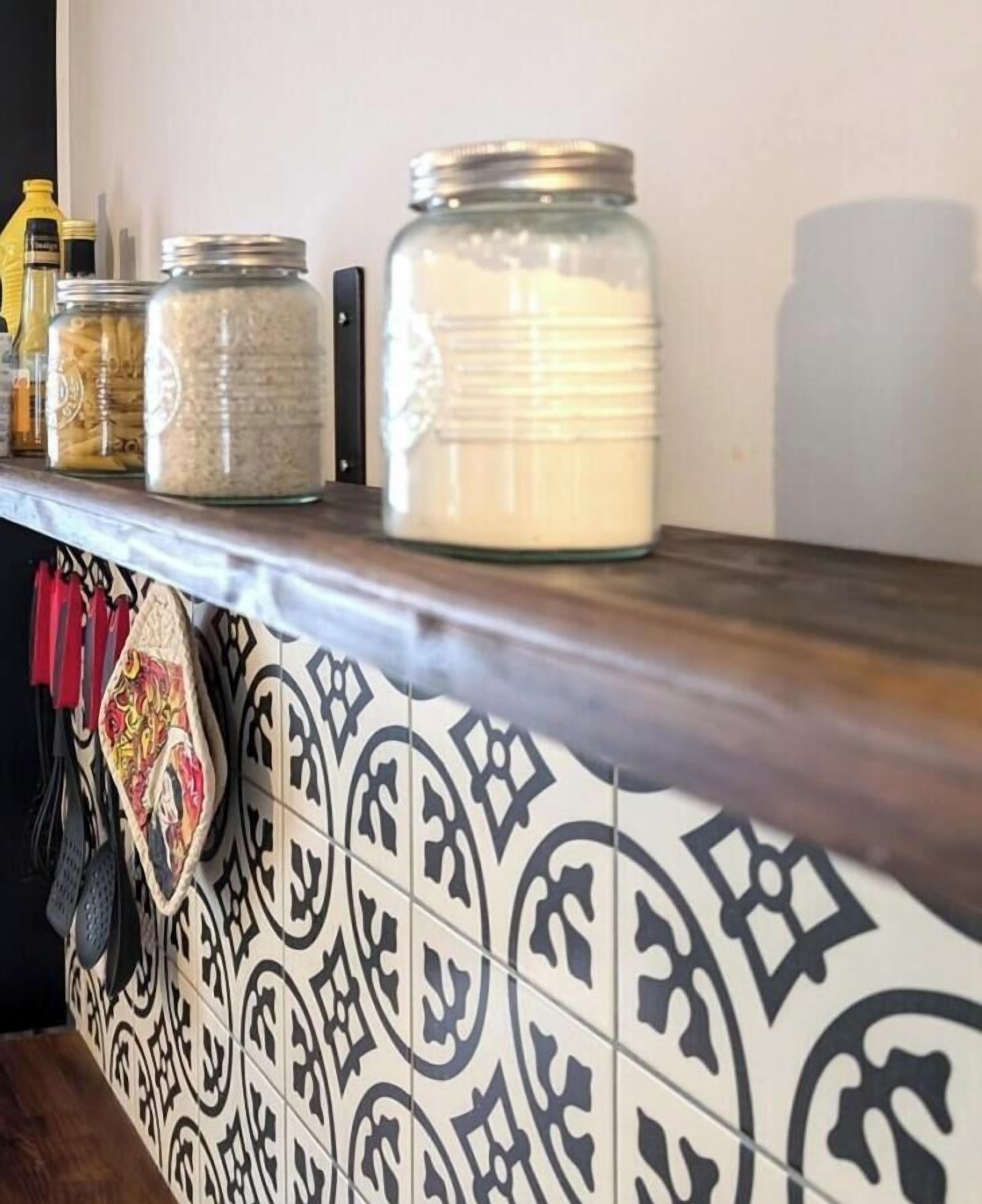 A kitchen shelf with jars of ingredients and a patterned backsplash.