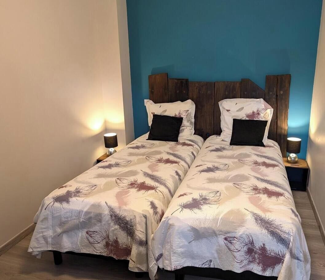 A double bed with feather-patterned bedding, two bedside tables with lamps, and a blue accent wall.